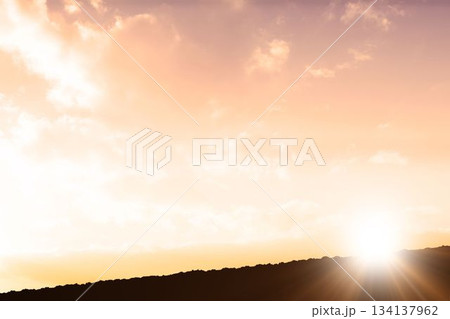 Sun is rising above ridge silhouette in flat design, casting glowing rays through scattered clouds Sun is rising above ridge silhouette in flat design, casting glowing rays through scattered clouds 134137962