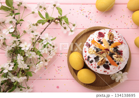 Traditional easter cakes with colorful sprinkles, with eggs, a bunny figurine, and spring flowers on pink wooden background Traditional easter cakes with colorful sprinkles, with eggs, a bunny figurine, and spring flowers on pink wooden background 134138695