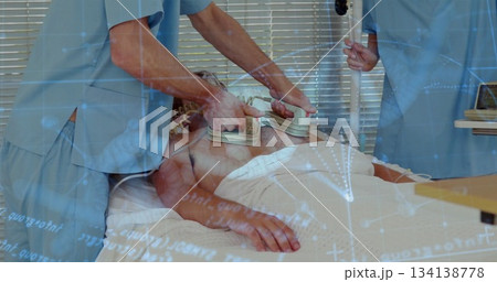 Defibrillating scrubclad team applying paddles and steadying IV pole to patient on ward bed Defibrillating scrubclad team applying paddles and steadying IV pole to patient on ward bed 134138778