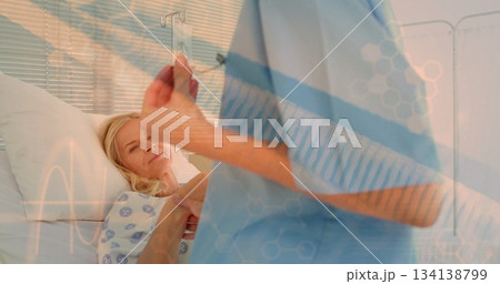 Nurse in scrubs aligning IV bag beside patient in hospital gown on bed in hospital room Nurse in scrubs aligning IV bag beside patient in hospital gown on bed in hospital room 134138799