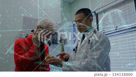 Pointing Asian doctor explaining prosthetic ear use to senior patient in exam room with DNA overlay Pointing Asian doctor explaining prosthetic ear use to senior patient in exam room with DNA overlay 134138800