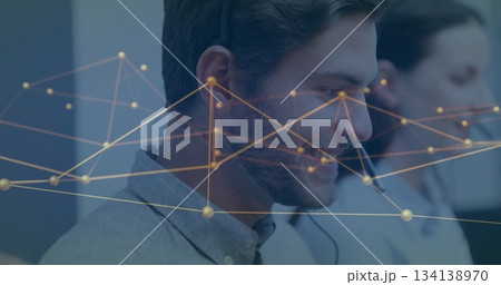 Customer service agent wearing gray shirt and headset analyzing network graph overlay at office Customer service agent wearing gray shirt and headset analyzing network graph overlay at office 134138970