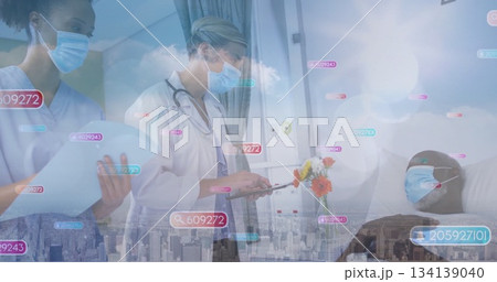 Writing doctor in lab coat documenting medical charts on clipboard at bedside with digital overlays 134139040