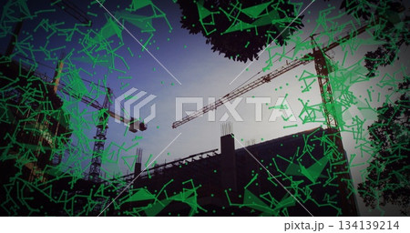 featuring three tower cranes around concrete frame at construction site at dusk, with green overlay featuring three tower cranes around concrete frame at construction site at dusk, with green overlay 134139214