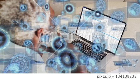 Leaning analyst analyzing spreadsheets on laptop at desk with UI graphics, copy space Leaning analyst analyzing spreadsheets on laptop at desk with UI graphics, copy space 134139235