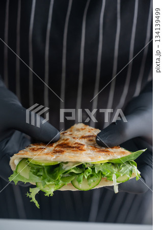 Chef holding a flatbread with herbs.  134139499