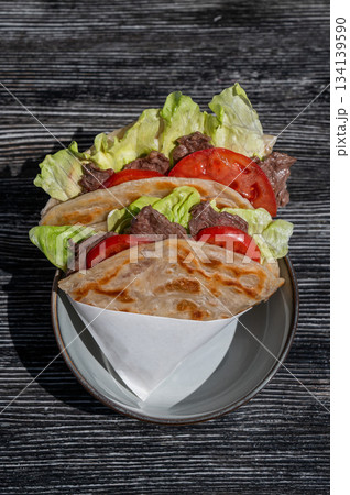 Homemade flatbread with beef and tomatoes on a table in a cafe.  134139590