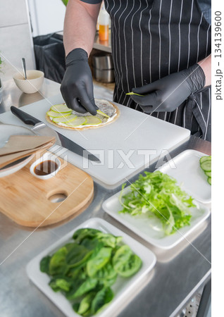 The chef prepares a flatbread with herbs.  134139600