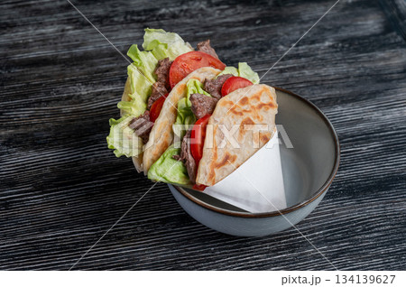 Homemade flatbread with beef and tomatoes on a table in a cafe.  134139627