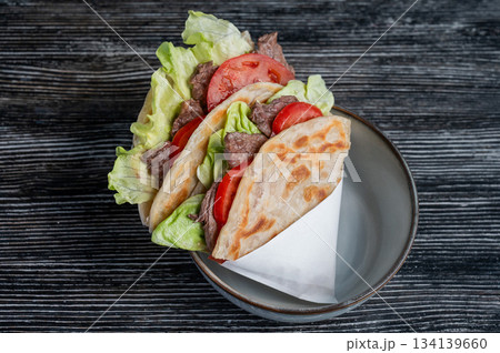 Homemade flatbread with beef and tomatoes on a table in a cafe.  134139660