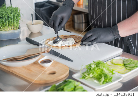 The chef prepares a flatbread with herbs.  134139911