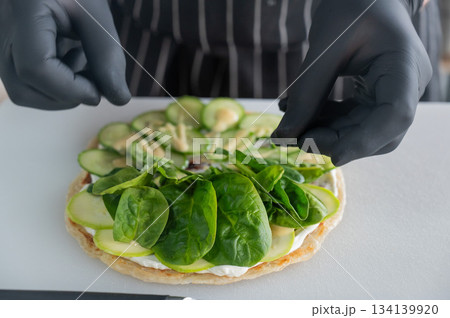 The chef prepares a flatbread with herbs. The chef prepares a flatbread with herbs. 134139920