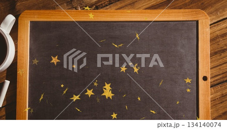 Featuring framed chalkboard lying flat on tabletop, with gold star confetti, coffee mug and chalk 134140074