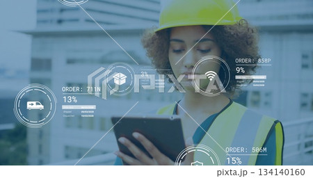 Reviewing engineer reading tablet on building site, with yellow safety helmet, reflective vest 134140160