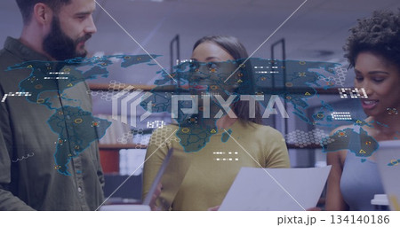 Three professionals wearing colorful tops discussing documents in office, with digital map overlay Three professionals wearing colorful tops discussing documents in office, with digital map overlay 134140186