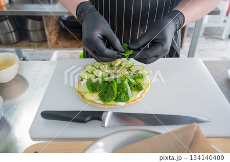 The chef prepares a flatbread with herbs. The chef prepares a flatbread with herbs. 134140409