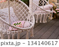 The swing is light wicker with a soft pillow in the style of macrome. Boho style, garden design. 134140617
