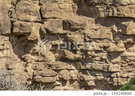 Rocky cliff formation showcases diverse textures and colors in a natural landscape at midday highlighting geological features and erosion patterns 134140686