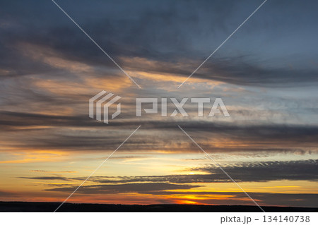 Colorful sunset over a vast landscape with vibrant clouds transitioning from day to night 134140738