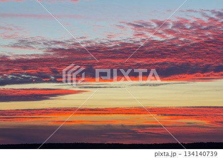 Vibrant sunset illuminates the sky with shades of orange pink and purple over a tranquil horizon at dusk 134140739