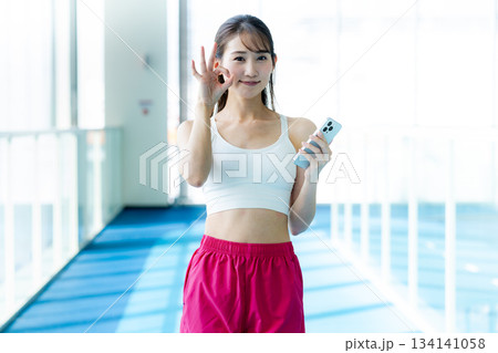 スポーツジムでスマホを持つ女性 スポーツジムでスマホを持つ女性 134141058
