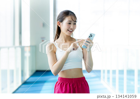 スポーツジムでスマホを持つ女性 134141059
