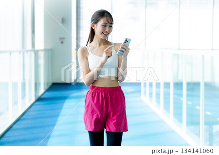 スポーツジムでスマホを持つ女性 134141060