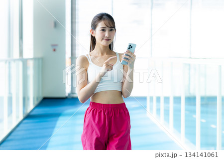 スポーツジムでスマホを持つ女性 134141061