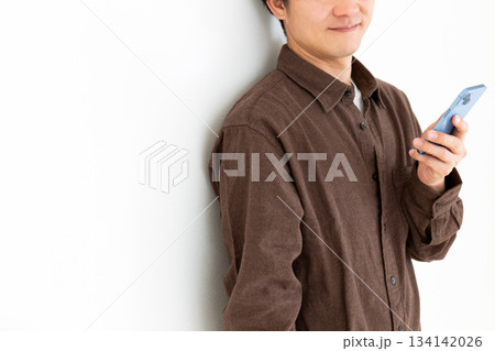 スマートフォンを持って微笑むカジュアル姿のミドル男性 スマートフォンを持って微笑むカジュアル姿のミドル男性 134142026
