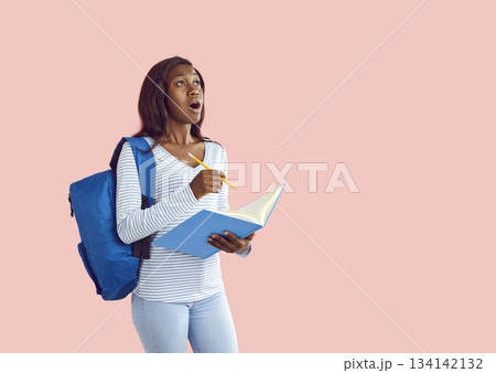 Portrait of shocked international student with paper notebook who came up with great idea. 134142132
