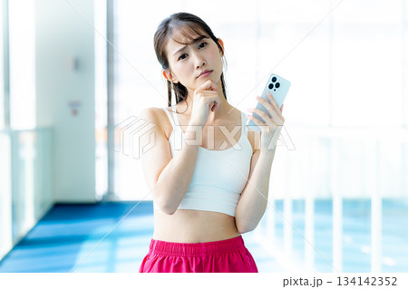 ジムでスマホを使う女性 ジムでスマホを使う女性 134142352