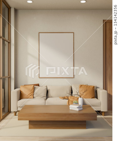 White frame on wall over sofa and wooden table with books and flower vase in a sun lit living room. 134142356