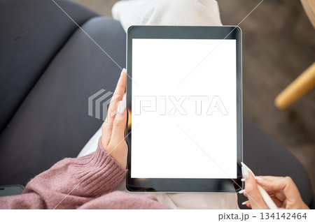 Close up of woman artist or student's hands holding tablet with stylus while sitting on sofa in cafe 134142464