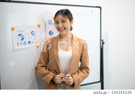 Asian businesswoman office worker holding a pen under chain looking at laptop on table in white room Asian businesswoman office worker holding a pen under chain looking at laptop on table in white room 134143126