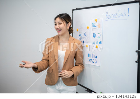 Asian businesswoman office worker holding a pen under chain looking at laptop on table in white room 134143128