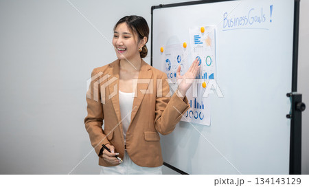 Asian businesswoman office worker holding a pen under chain looking at laptop on table in white room Asian businesswoman office worker holding a pen under chain looking at laptop on table in white room 134143129