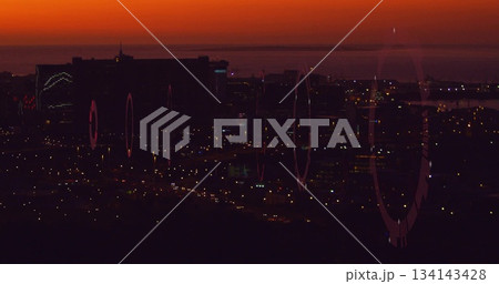 Showing skyline with high-rise buildings glowing at dusk from hillside ridge, with lens flares 134143428