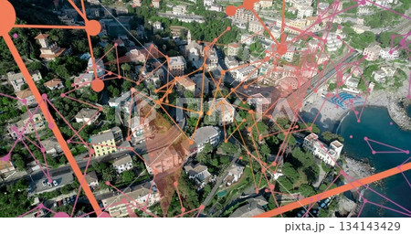 Showing aerial hillside village overlaying network across pastel roads, pebble beach and blue water 134143429