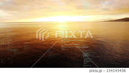 Glowing sun scattering golden reflection on ocean surface at dusk, with clouds and far coastline Glowing sun scattering golden reflection on ocean surface at dusk, with clouds and far coastline 134143436