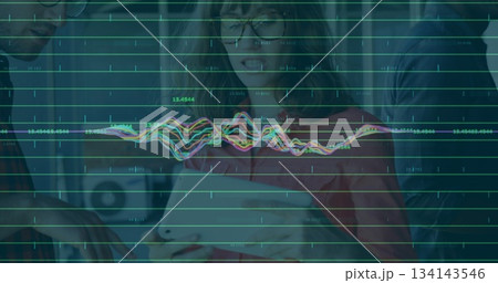 Collaborating team analyzing data on tablet in office, with green data line graphs and waveforms 134143546