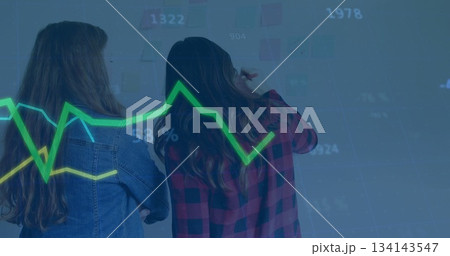 Two colleagues marking sticky notes and referencing graph in conference room, with markers 134143547