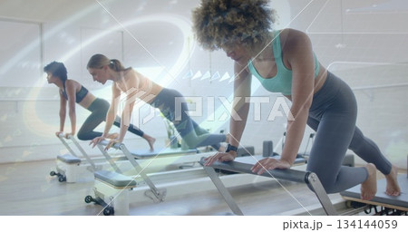 Pushing woman wearing teal sports bra and leggings using reformers in Pilates studio, copy space Pushing woman wearing teal sports bra and leggings using reformers in Pilates studio, copy space 134144059
