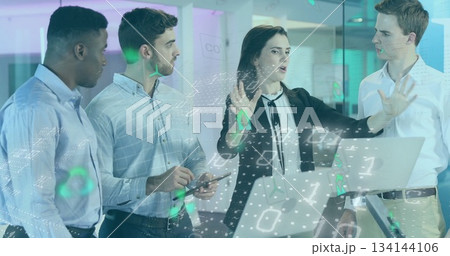 Gesturing woman in blazer presenting holographic code overlay in office, with laptop and smartphone 134144106