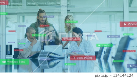 Collaborating five professionals showing software features in glass office, with laptops and tablet 134144124