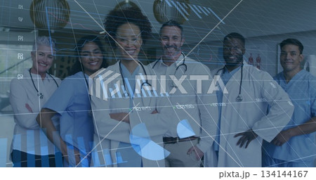 Standing medical team smiling in hospital corridor, with stethoscopes, scrubs and lab coats 134144167