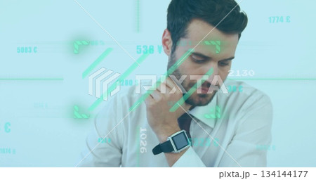 Businessman wearing shirt and tie sitting in office checking smartwatch, with financial graphics Businessman wearing shirt and tie sitting in office checking smartwatch, with financial graphics 134144177