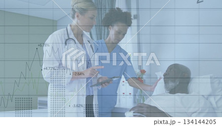 Reviewing doctor and nurse in scrubs consulting patient data on tablet at bedside, with IV stand 134144205