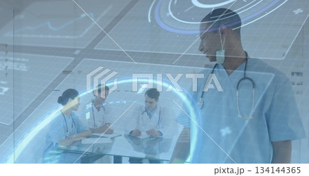 Standing doctor in scrubs watching team reviewing clipboards with holograms in hospital, copy space 134144365