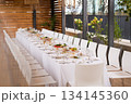 Wide shot of long set table on terrace with city view - elegant table setting for event 134145360