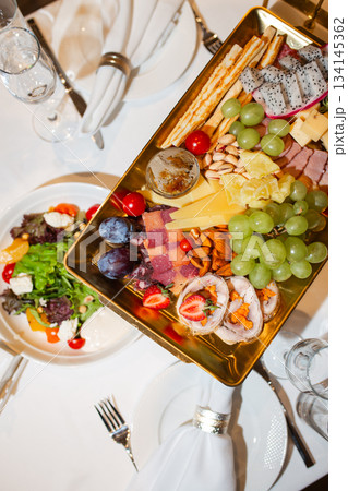 Top view of golden tray with cheese, fruit and appetizer assortment - luxurious buffet Top view of golden tray with cheese, fruit and appetizer assortment - luxurious buffet 134145362